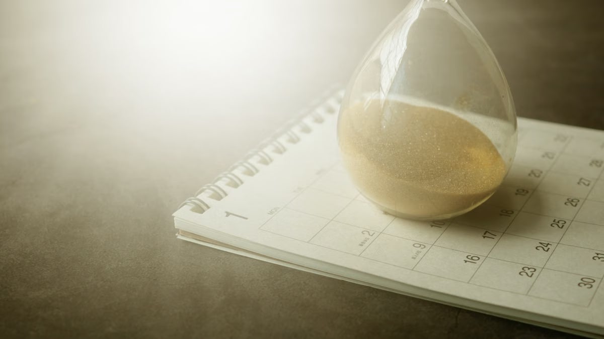 An hourglass on a calendar captures the essence of time management and urgency.